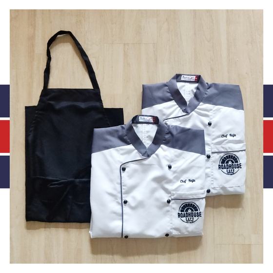 Two white chef coats with grey collar, black piping and printed logo, with black bib apron, custom made for Roadhouse Cafe by RestroCart, New Delhi