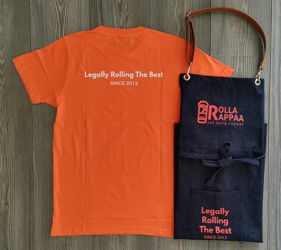 Orange round neck t-shirt with white printed slogan and dark denim bib apron with leather strap and red print, custom made by RestroCart, New Delhi