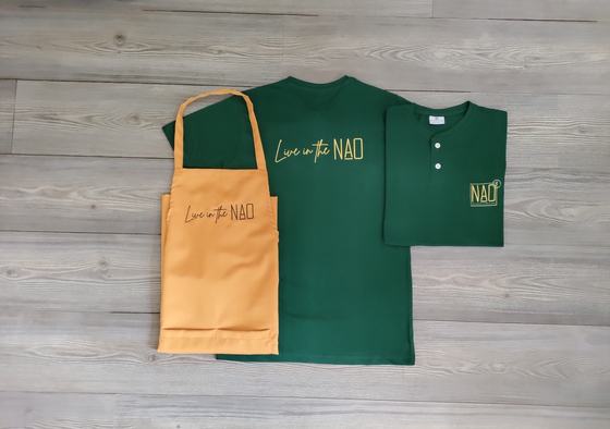 Dark green round neck t-shirt, green henley tee and mustard bib apron with gold script logo, laid flat, custom made by RestroCart, New Delhi