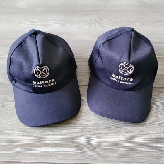 Two navy baseball caps with white embroidered round logo and name on front, custom made for Saltaro Coffee Roasters by RestroCart, New Delhi