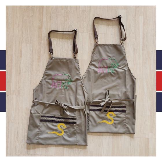 Two khaki bib aprons with leather straps, pink elephant and yellow S embroidery, striped pockets, custom made for Satay by RestroCart, New Delhi