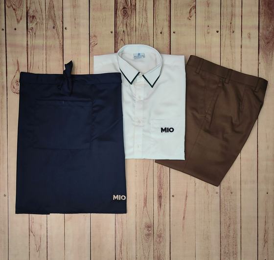 Cream shirt with black collar piping, navy waist apron and brown trousers with white print logo, custom made by RestroCart, New Delhi