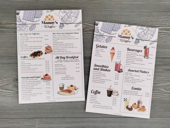 Two white sunboard menu sheets with sketched illustrations and dish photos, on grey wood, custom made by RestroCart, New Delhi