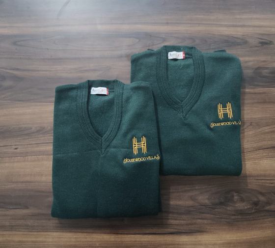 Two bottle green V-neck knit sweaters with gold embroidered logo, folded, custom made by RestroCart, New Delhi