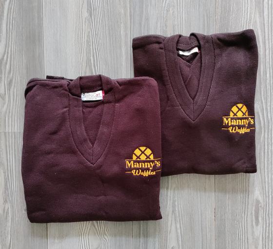 Two maroon V-neck knit sweaters with yellow embroidered waffle logo, folded, custom made by RestroCart, New Delhi