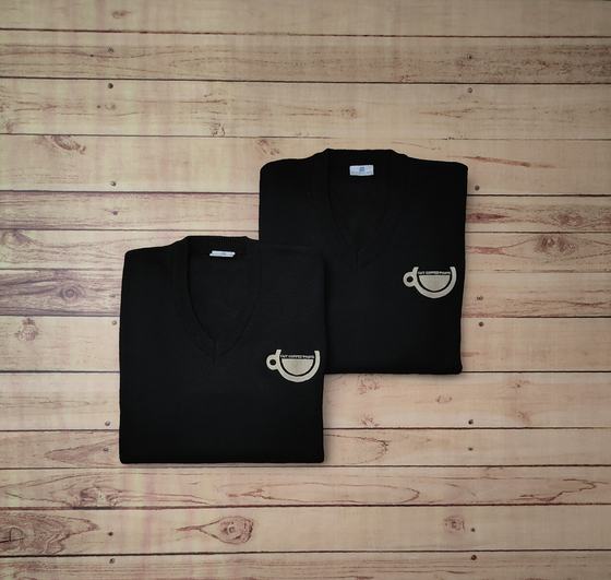 Pair of folded black V-neck sweaters with beige embroidered coffee cup logo on the chest, on wood, custom made by RestroCart, New Delhi