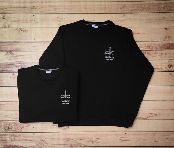 Black fleece sweatshirts with white embroidered cafe logo on the chest, one folded and one flat, custom made by RestroCart, New Delhi
