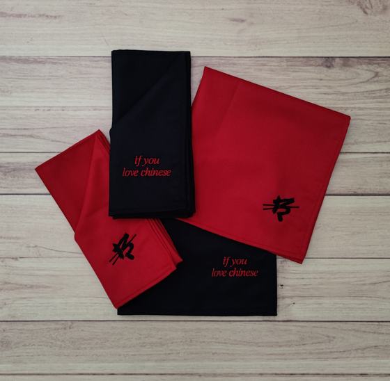 Red and black cloth table napkins with embroidered script slogan and symbol, folded and fanned out, custom made by RestroCart, New Delhi
