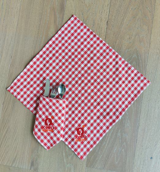 Opened red and white gingham napkin with cutlery tucked in its pocket and red printed logo, custom made by RestroCart, New Delhi