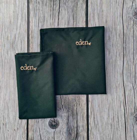 Dark green cloth table napkins with gold embroidered script logo, one folded and one laid flat, custom made by RestroCart, New Delhi
