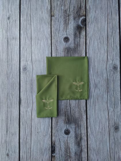 Olive green cloth table napkins with tonal embroidered bird logo in the corner, custom made by RestroCart, New Delhi