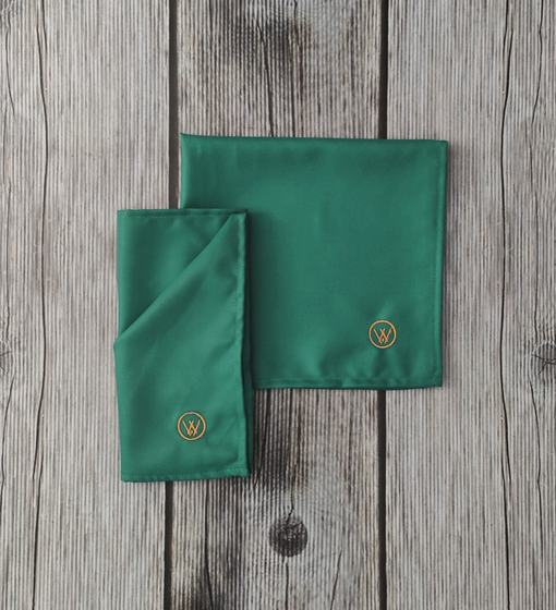 Teal cloth table napkins with gold embroidered round monogram, one folded in half, custom made by RestroCart, New Delhi