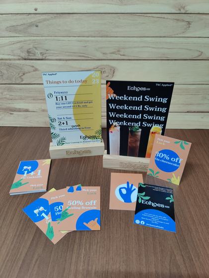 Printed promo tent cards in engraved pine wood stands with matching offer flyers spread in front, custom made by RestroCart, New Delhi