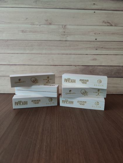 Stacked white wooden table stand blocks with engraved logos of several cafes, on a wooden table, custom made by RestroCart, New Delhi