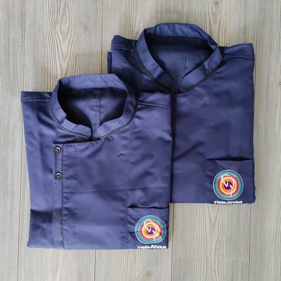 Two navy chef coats with dark piping and round embroidered logo on pocket, folded on grey wood, custom made for Thalaivar by RestroCart, New Delhi