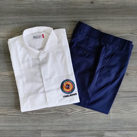 White full sleeve shirt with round logo patch and folded navy trousers, laid flat on grey wood, custom made for Thalaivar by RestroCart, New Delhi