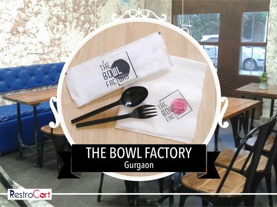 White cutlery pouches with black and red printed logo and a black plastic spoon and fork, custom made for The Bowl Factory by RestroCart, New Delhi