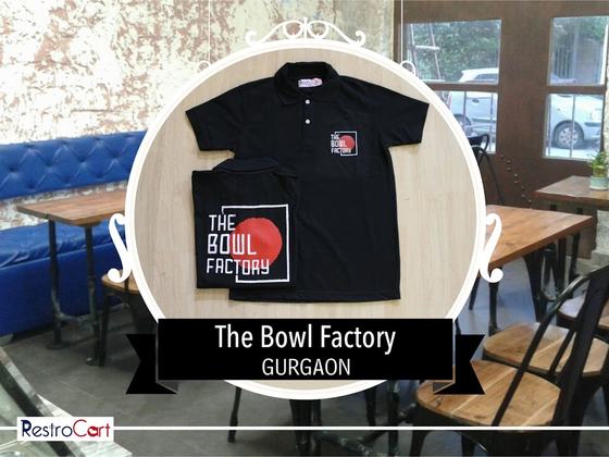 Black polo t-shirt with red and white logo and a black waist apron with large logo print, custom made for The Bowl Factory by RestroCart, New Delhi