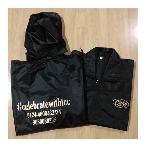 Black hooded raincoats with gold printed hashtag and phone numbers on back, folded, custom made for The Cake Company by RestroCart, New Delhi