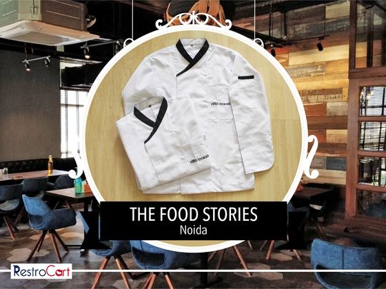 White chef coats with black crossover collar and cuffs and small logo, one folded, custom made for The Food Stories by RestroCart, New Delhi
