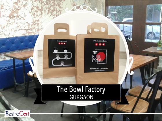 Two kraft paper carry bags with die-cut handles and black printed home delivery labels, custom made by RestroCart, New Delhi