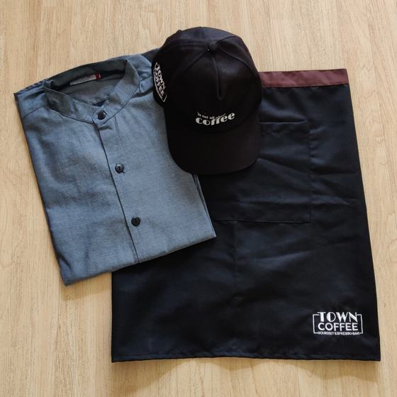 Black waist apron with maroon band and printed logo, grey mandarin collar shirt and black cap, custom made for Town Coffee by RestroCart, New Delhi