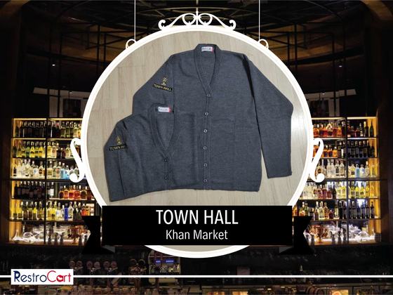 Two charcoal grey knitted cardigans with small gold embroidered logo, one folded, custom made for Townhall by RestroCart, New Delhi