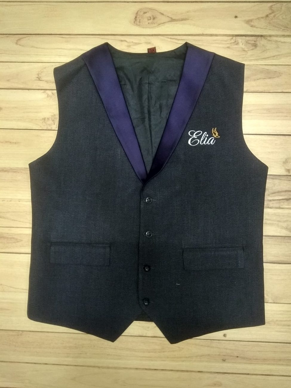 Charcoal service waistcoat with a contrast purple shawl lapel, welt pockets and white script embroidery with a gold motif on the chest, made by RestroCart, New Delhi