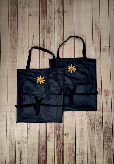 Two black waterproof bib aprons with yellow printed star emblem, one overlapping the other, custom made by RestroCart, New Delhi