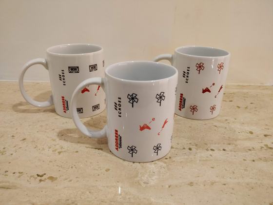 Three white ceramic mugs with small red and black repeat icon prints on a marble counter, custom made by RestroCart, New Delhi