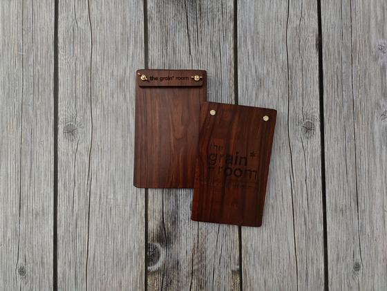 Pair of dark walnut wood menu clipboards with engraved header strip and printed wordmark, on grey wood, custom made by RestroCart, New Delhi