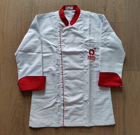 White chef coat with red collar and red cuffs, red piping and embroidered chest logo, custom made for Xero Degrees by RestroCart, New Delhi